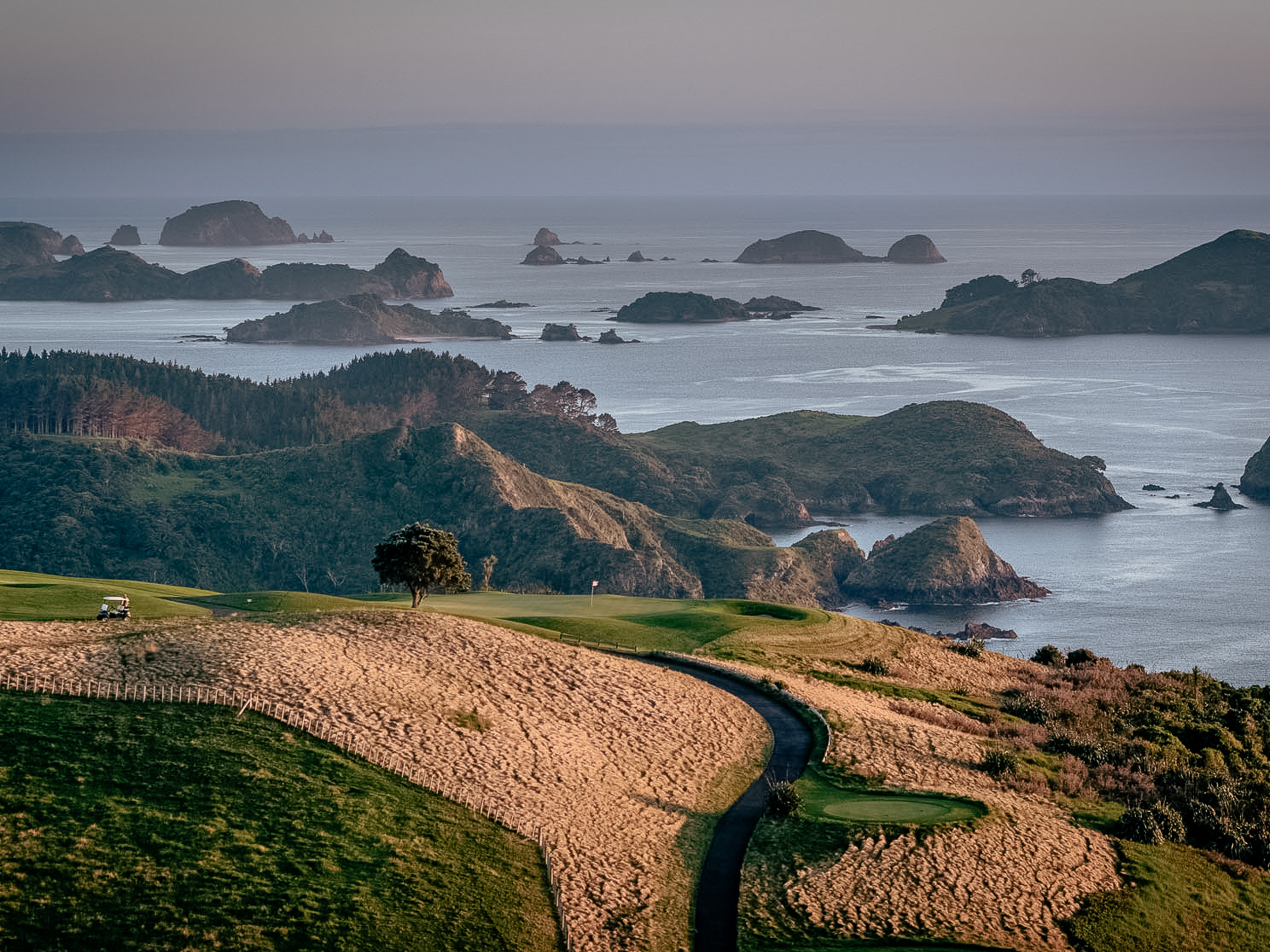 Scenic golf course overlooking rugged islands and calm ocean waters.